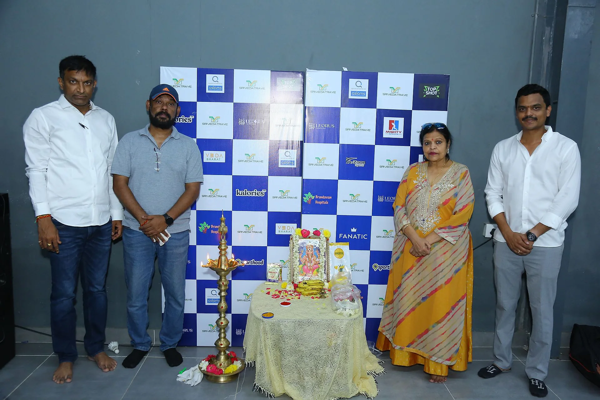 Organisers and a guest standing beside the lit lamp at the inauguration
