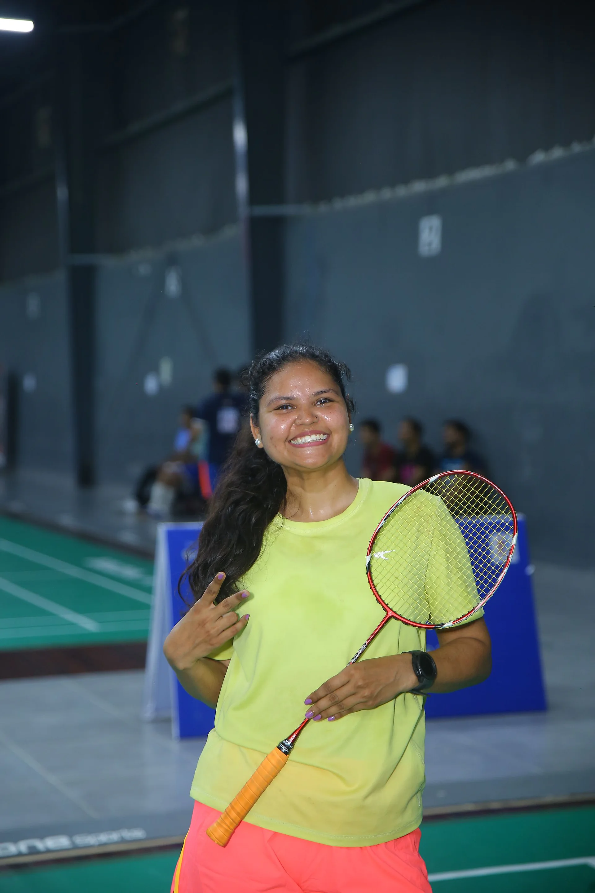 A smiling player holding a racket on the badminton court