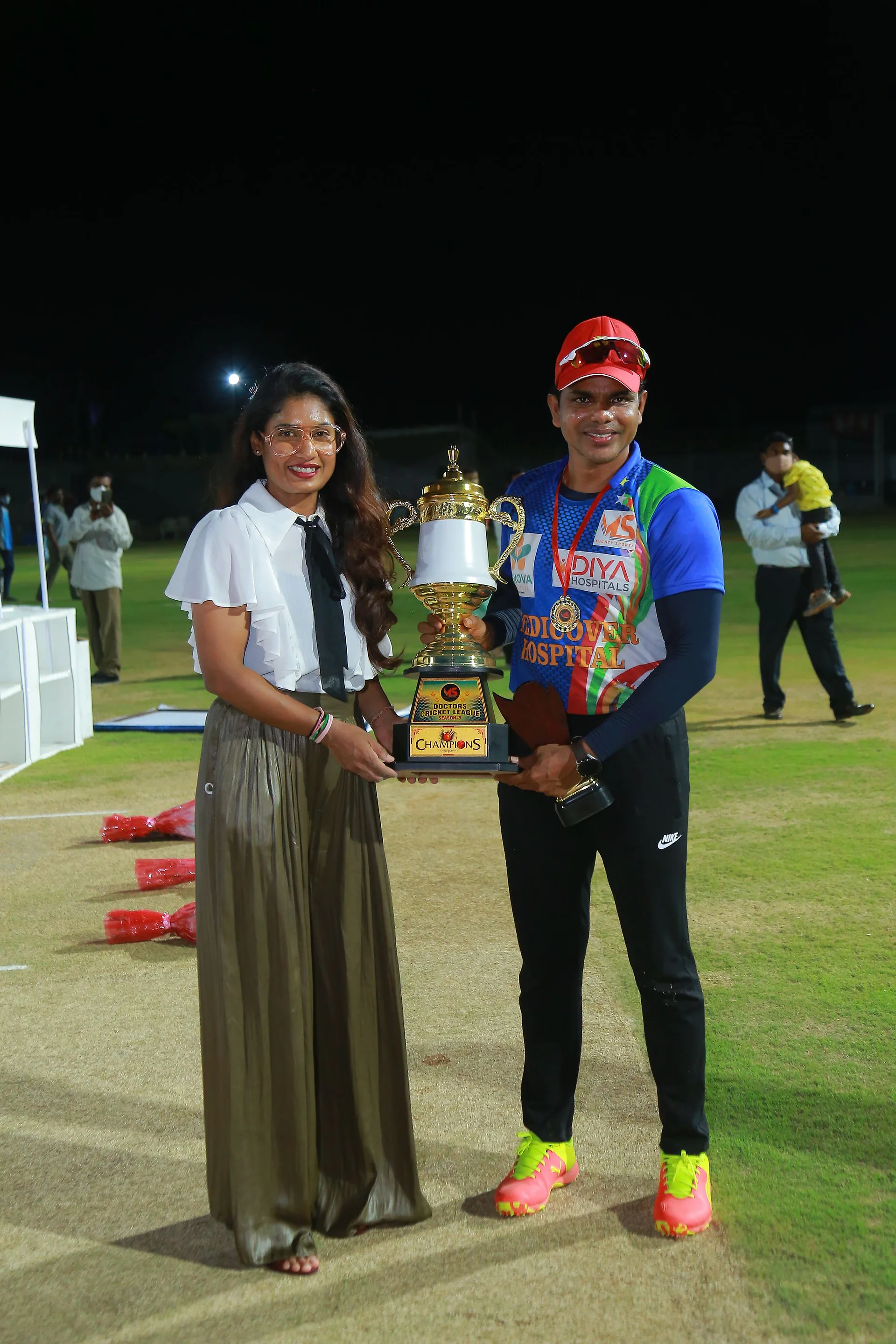 A player receiving the winners' trophy on the ground at night