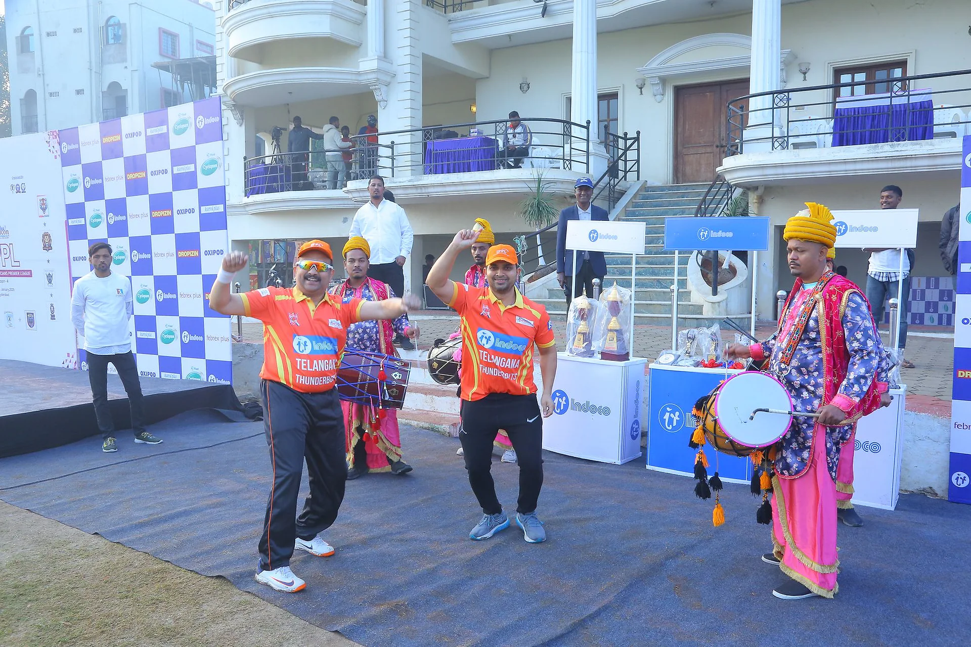 Players in orange jerseys celebrating with a drummer at the IPPL