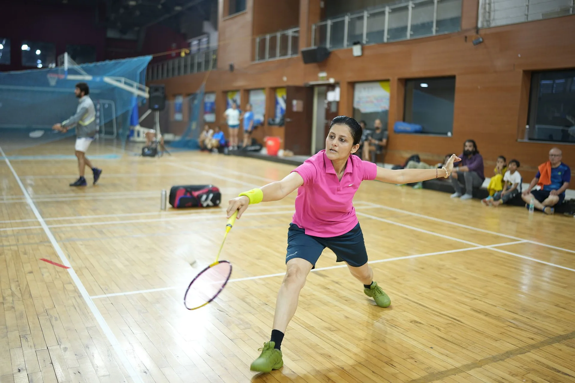 A player in a pink top reaching wide for a shot