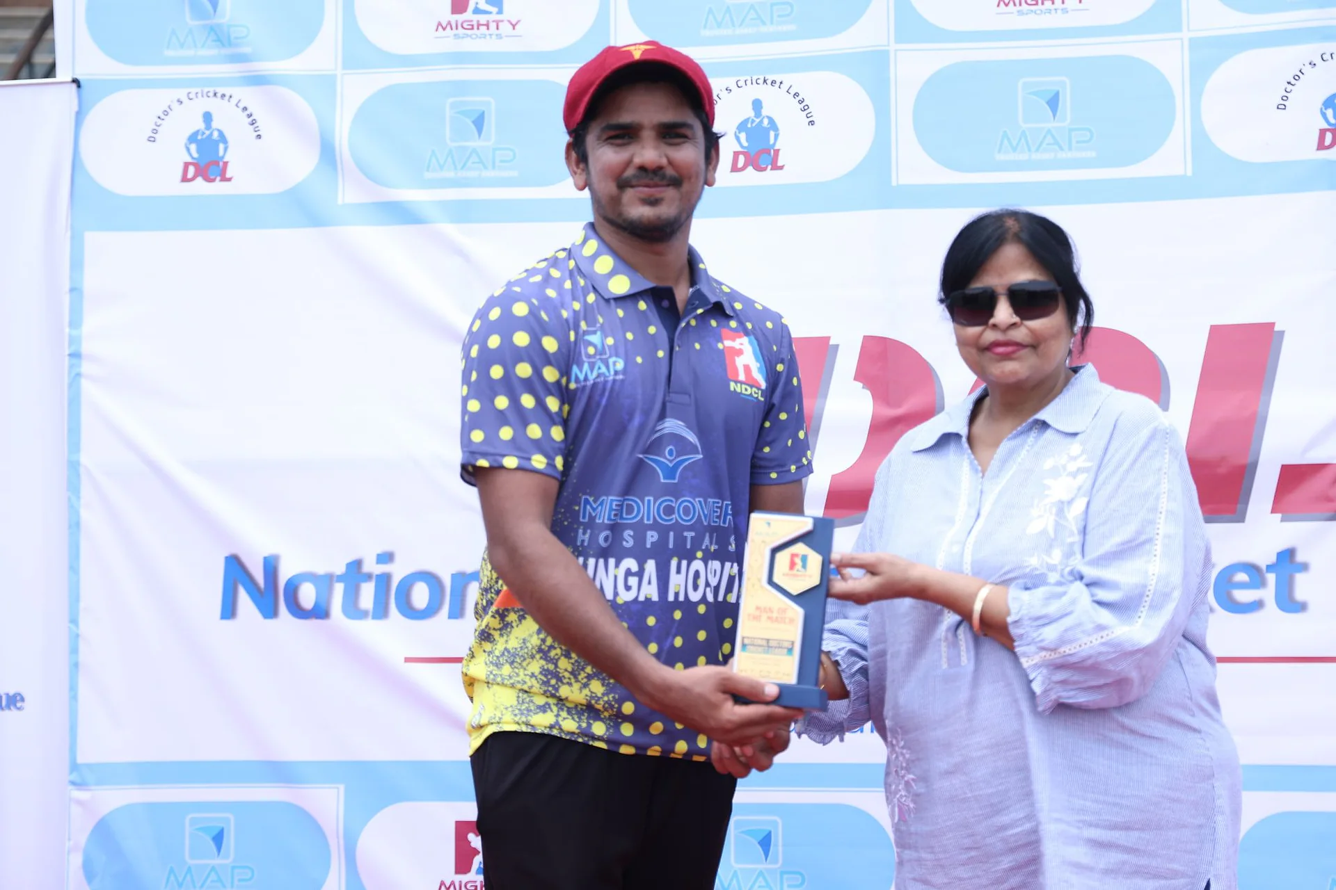 A player in a patterned cricket shirt receiving an award at the National Doctors Cricket League