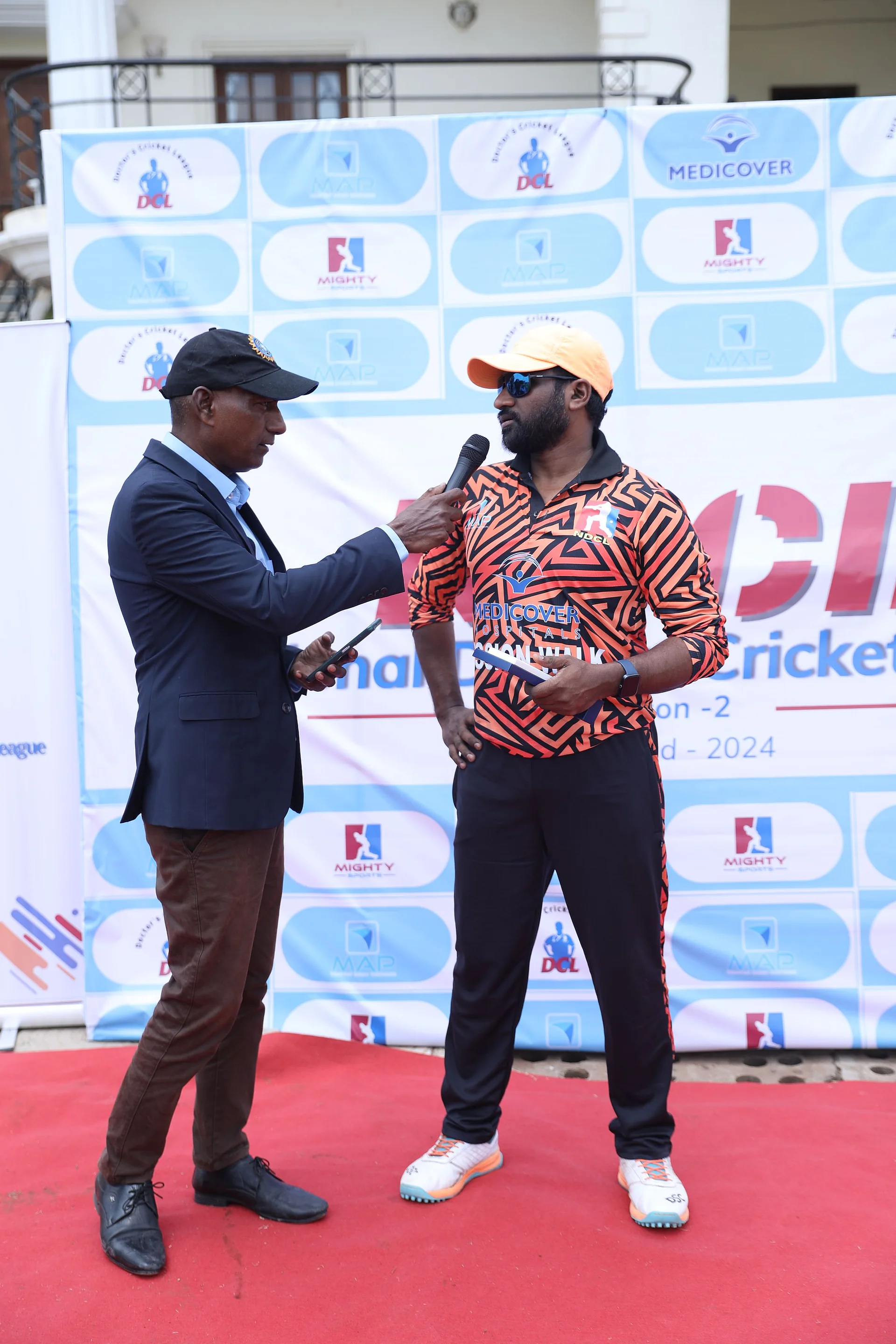A presenter interviewing a player on the red carpet at the National Doctors Cricket League